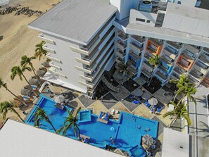 Un hôtel de grande hauteur doté d’une piscine sur le toit, de nombreux balcons et offrant une vue sur la plage.