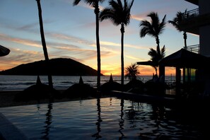 A sunset view with palm trees and a pool. - Star Palace Hotel (Mazatlán)