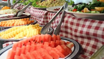 Una mesa de buffet con diferentes alimentos como sandía, queso y ensaladas.