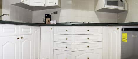 A kitchen with white cabinets, a microwave, and a coffee maker.