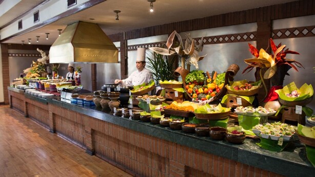 Een buffetopstelling met diverse gerechten en een kok die eten bereidt.