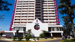 Een meerlaags hotel met een centrale atriumhal, balkons op elke verdieping en een opvallende entree met een rond logo.