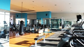 Een sportschool met trainingsapparatuur, een bokszak en een bank.