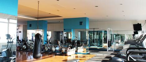 A gym with exercise equipment, a punching bag, and a bench.