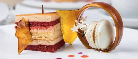 A dessert plate with a layered cake, a macaron, and a decorative glass.