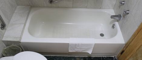 Ein Badezimmer mit Badewanne, Toilette und einer Haltestange.