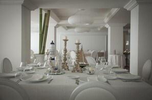 A formal dining room with a long table set for a meal, featuring white tablecloths, elegant tableware, and decorative candle holders. - Le Saline Resort (Montebello Ionico)