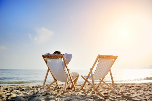 Na praia, areia branca, espreguiçadeiras, guarda-sóis 
