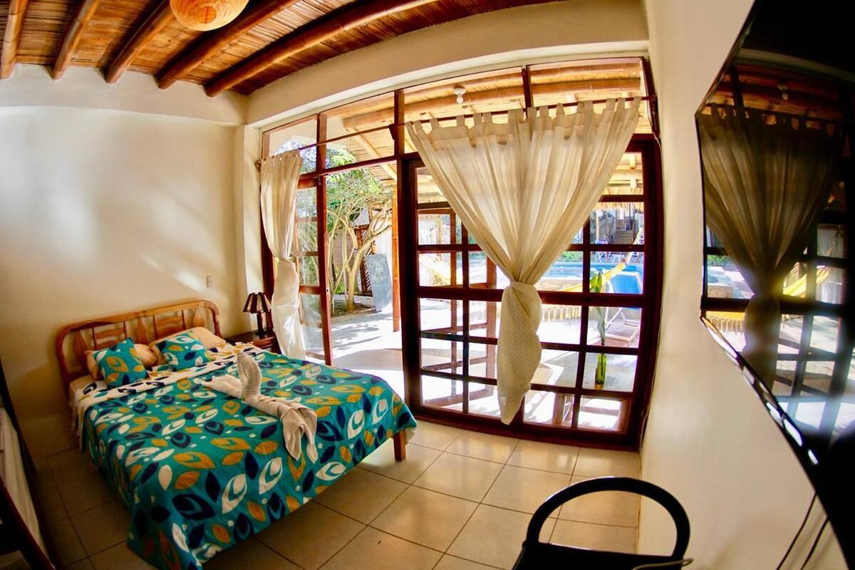 A bedroom with a bed, a chair, and a window with curtains.