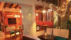 Ein gemütliches Restaurant mit Korbmöbeln, Holzbalken und Lichterketten.