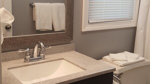 Un baño con lavamanos, espejo e inodoro.
