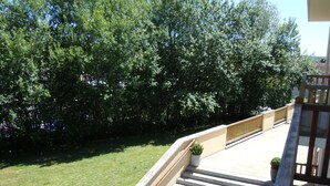 A staircase leading to a balcony with a view of a grassy area and trees. - Sweet Home Appart Hotel Deauville Sud (Saint-Arnoult)