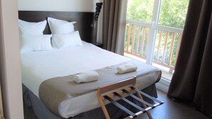 A neatly made bed with white linens and two rolled towels, a wooden chair, and a balcony with a railing. - Sweet Home Appart Hotel Deauville Sud (Saint-Arnoult)