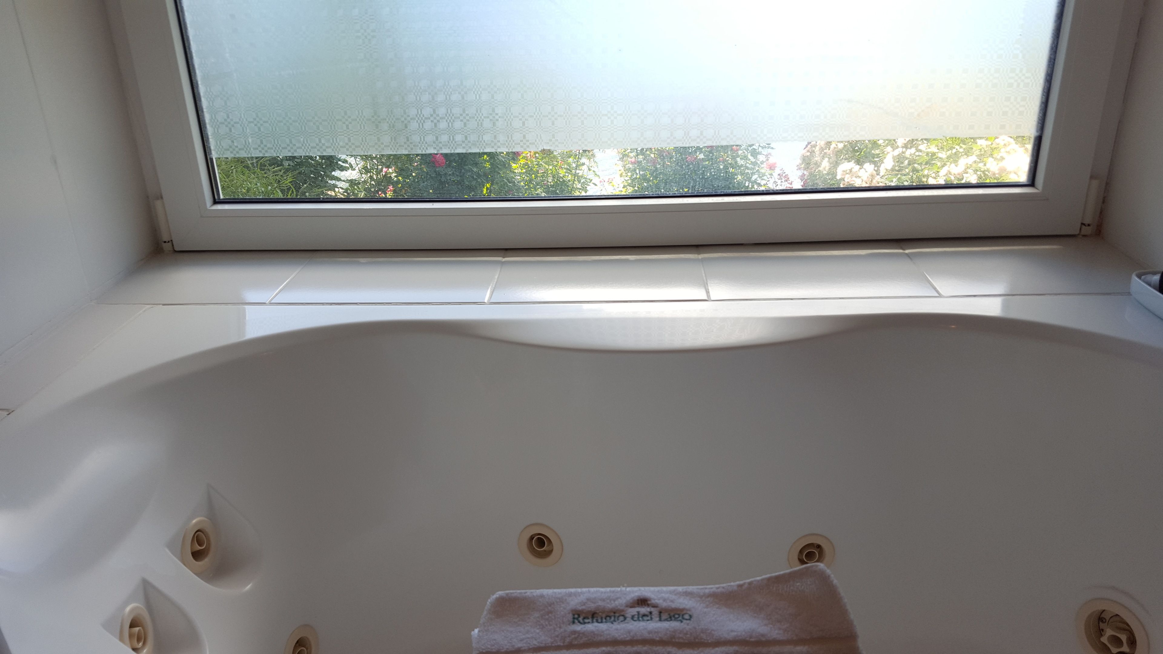 A bathroom with a bathtub, a window, and a towel rack.