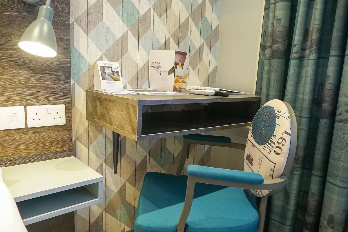 Una habitación de hotel moderna con un escritorio, una silla y una lámpara.