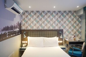 Habitación de hotel con cama, escritorio, silla, teléfono y aire acondicionado instalado en la pared.