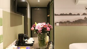 Ein Hotelzimmer mit Kaffeemaschine, Blumen in einer Vase und einem Bild an der Wand.