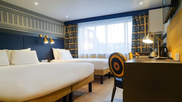 Ein Hotelzimmer mit zwei Betten, einem Schreibtisch und einem Stuhl.