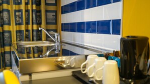 Ein modernes Badezimmer mit einem in Glas eingefassten Waschbecken, einer Kaffeemaschine und einem Tablett mit weißen Tassen.