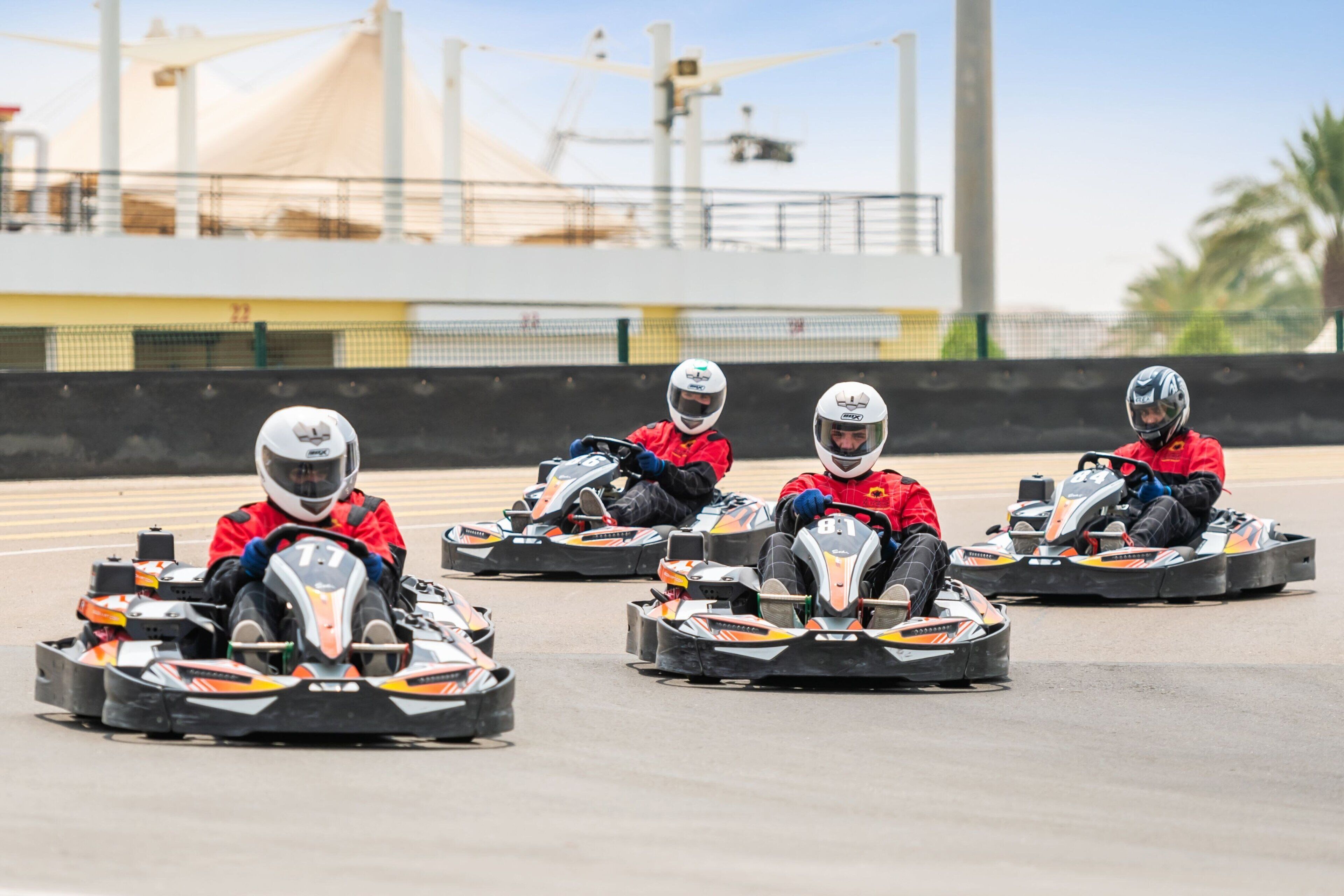 Pista de carreras de karts con varios karts y conductores con uniformes rojos.