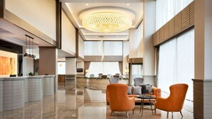 A spacious lobby with a polished marble floor, a central seating area with orange chairs, and a large chandelier. - Ramada by Wyndham Iskenderun (Iskenderun)