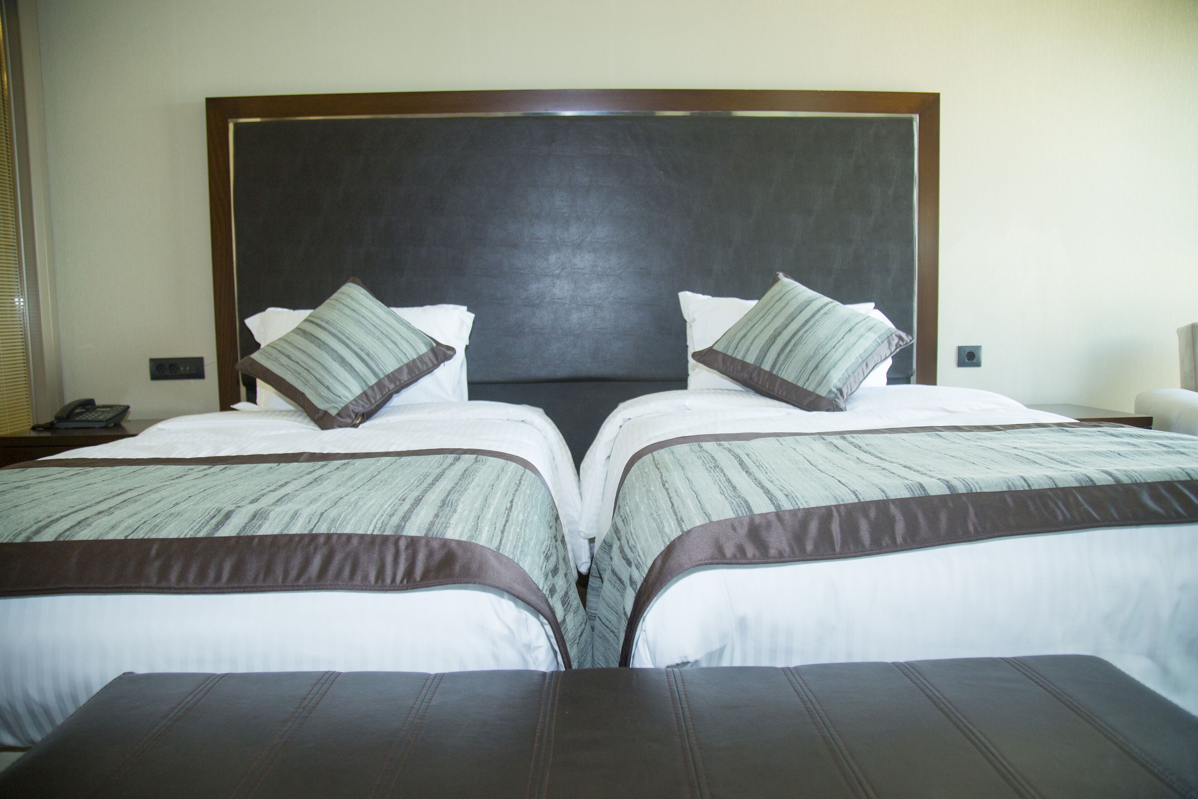 A hotel room with a large bed, two pillows, and a headboard.