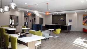 A hotel lobby with a reception desk, seating areas, and a large mirror. - Days Inn & Suites by Wyndham Houston NW Cypress (Houston)