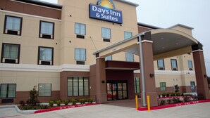 A Days Inn & Suites building with a covered entrance, multiple windows, and a fire lane marked on the ground. - Days Inn & Suites by Wyndham Houston NW Cypress (Houston)