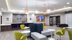 A hotel lobby with a reception desk, seating areas, and a large cityscape painting. - Days Inn & Suites by Wyndham Houston NW Cypress (Houston)