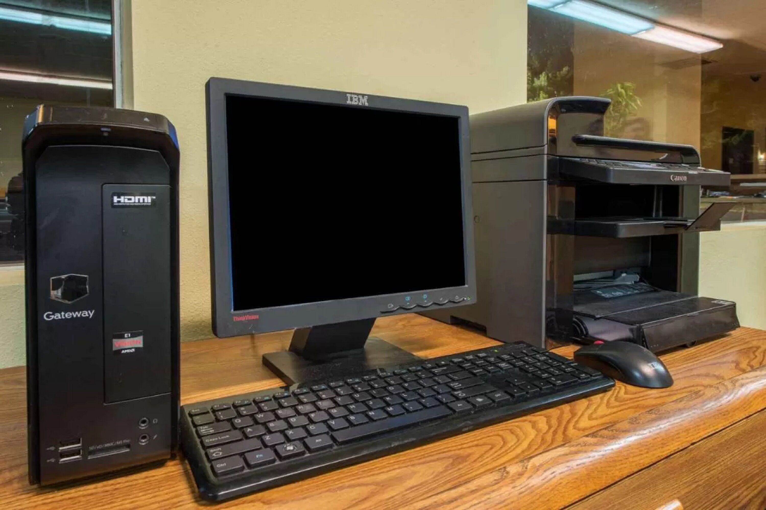 Una computadora de escritorio Gateway con un monitor y una impresora sobre un escritorio de madera.