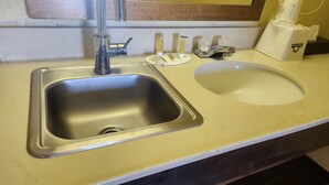 Un lavabo dans la salle de bain, avec un miroir au-dessus, un distributeur de savon et un distributeur de serviettes.