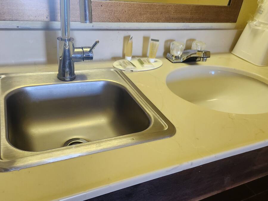 A bathroom sink with a mirror above it, a soap dispenser, and a towel dispenser.