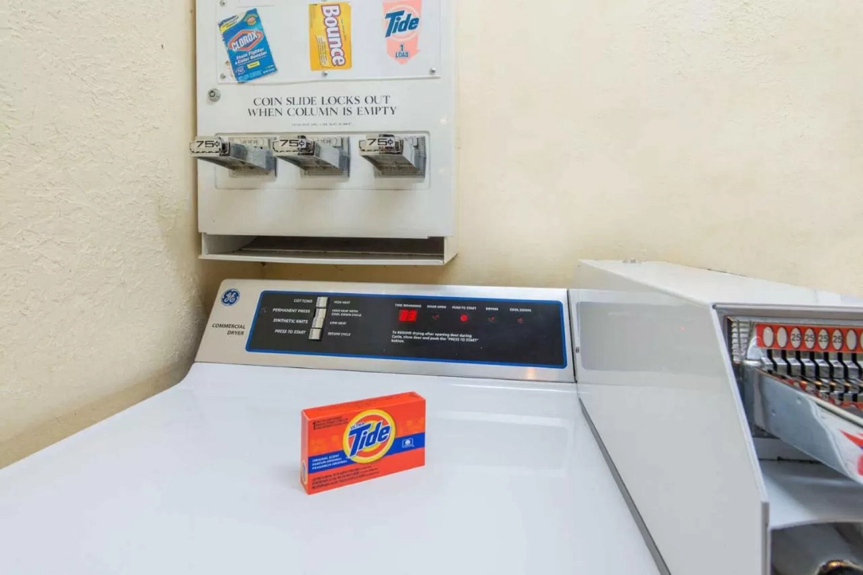 A coin-operated laundry machine with Tide detergent.