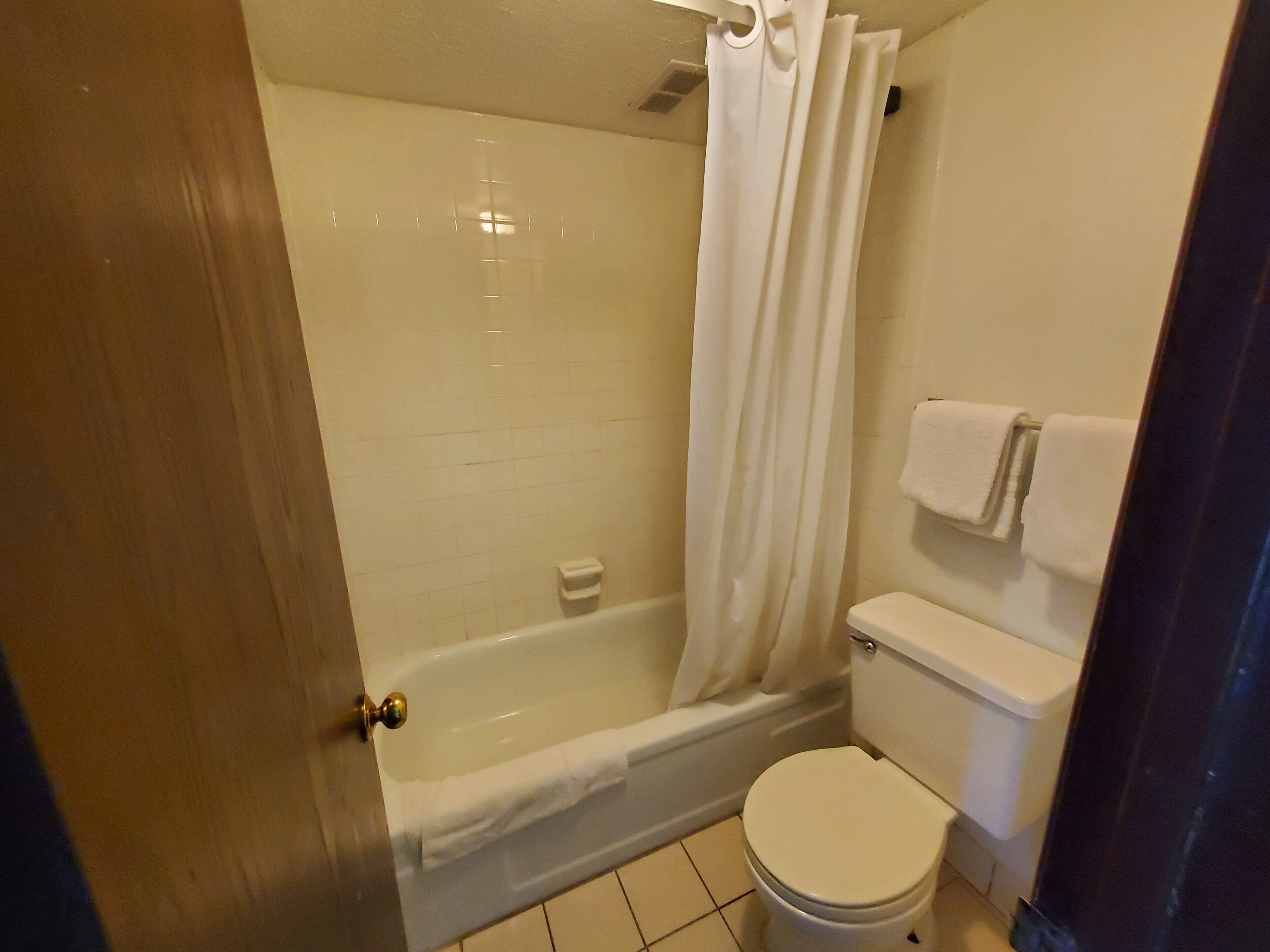 Un baño con bañera, inodoro y cortina de ducha.