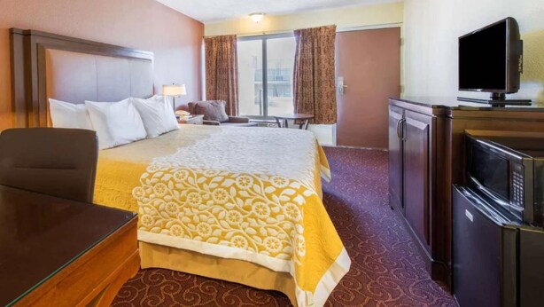 Une chambre d’hôtel avec un grand lit, un bureau, une télévision et un réfrigérateur.