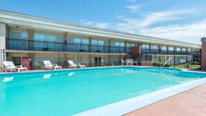Un hôtel doté d’une piscine, de chaises longues et d’une passerelle couverte.