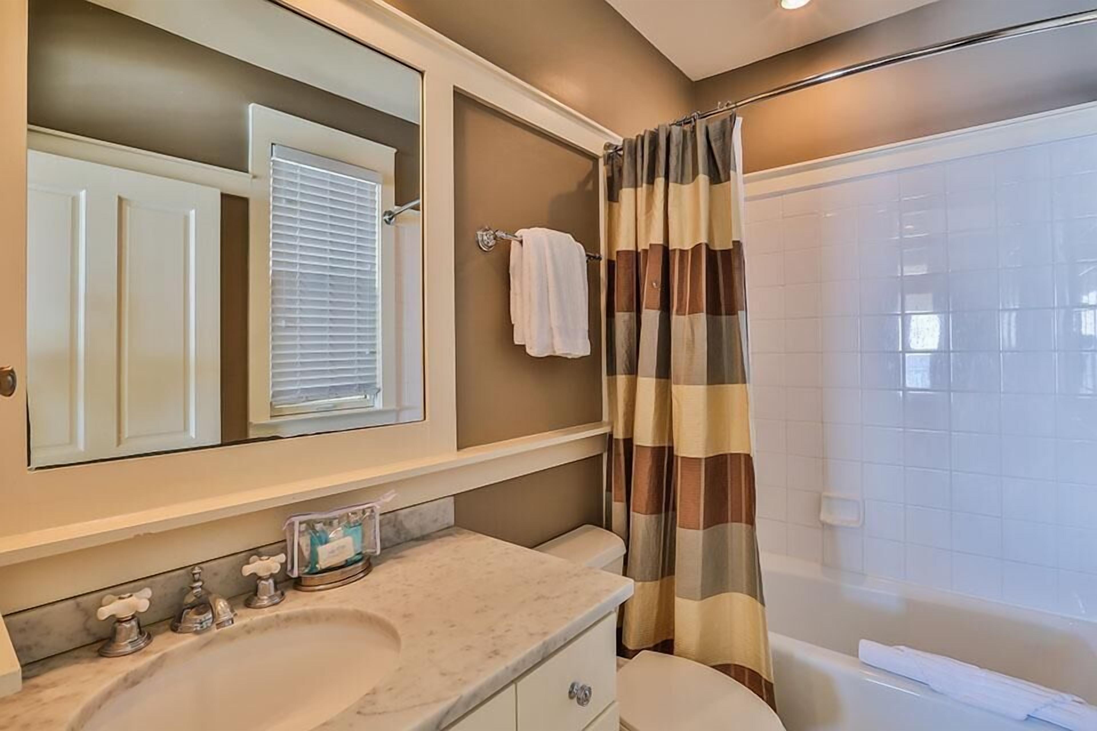 A bathroom with a white sink, a mirror above it, a towel rack, and a shower curtain.