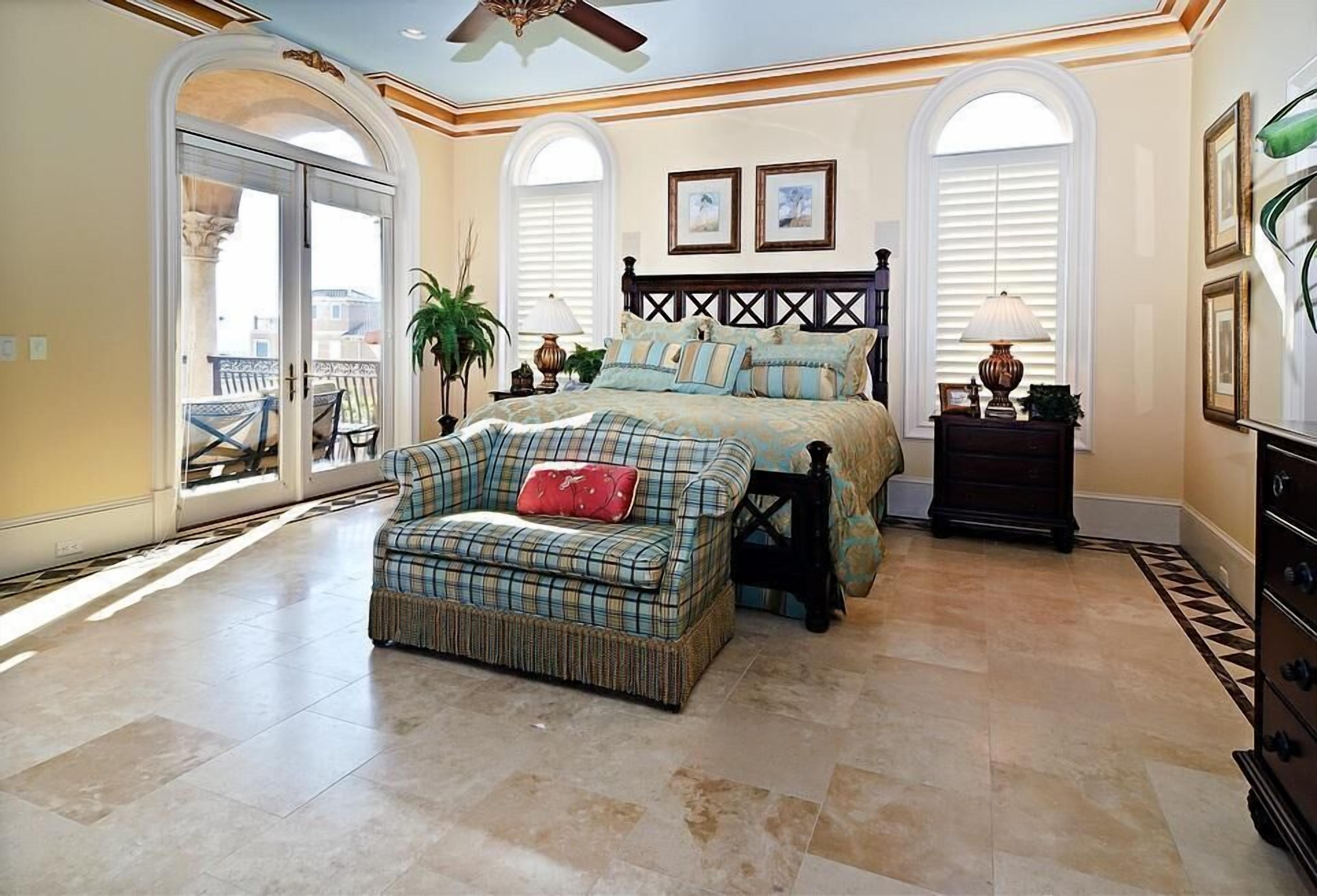 A bedroom with a bed, a chaise lounge, a dresser, and a ceiling fan.