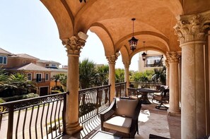 A covered outdoor area with columns, wicker furniture, and a view of the surrounding neighborhood. - Vista del Mare 4 Bedroom Holiday Home by Five Star Properties (Destin)