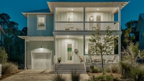 Ein zweistöckiges Haus mit verdeckter Veranda, Garage und kleinem Vorgarten mit Pflanzen.