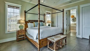 A four-poster bed with a wooden frame, a bedside table with a lamp, and a bench.
