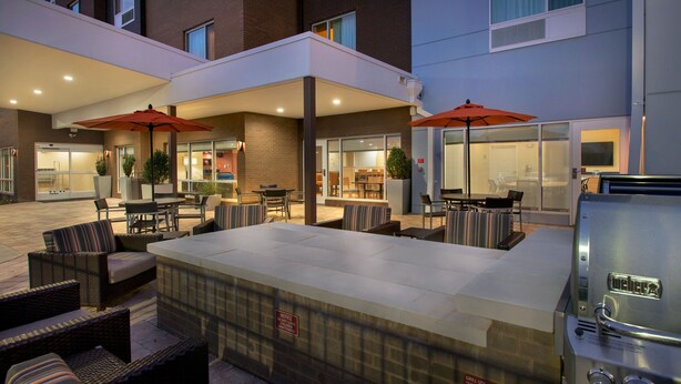 An outdoor patio area with seating, a hot tub, and a grill.