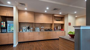 A modern kitchen with wooden cabinets, a stainless steel refrigerator, and a bowl of green apples on the counter.