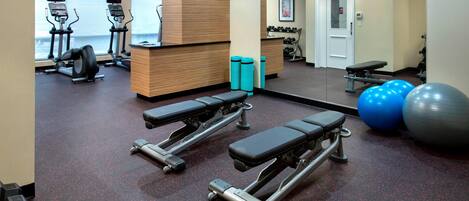 A gym with treadmills, weight benches, dumbbells, and exercise balls.
