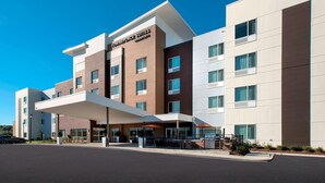 A modern hotel with a prominent 'Towneplace Suites Marriott' sign, a covered entrance, and a parking area.