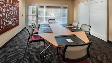 A conference room with a large table, chairs, and a carpeted floor.