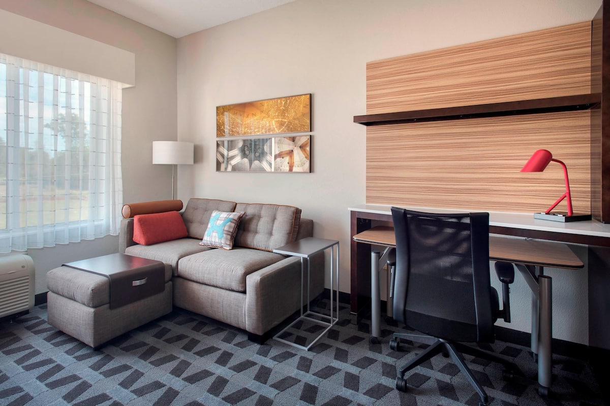 Une chambre d’hôtel moderne, équipée d’un canapé, d’un bureau, d’une chaise et d’une lampe.
