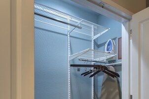 Un armario con un estante metálico, una barra para colgar ropa y una pared azul.