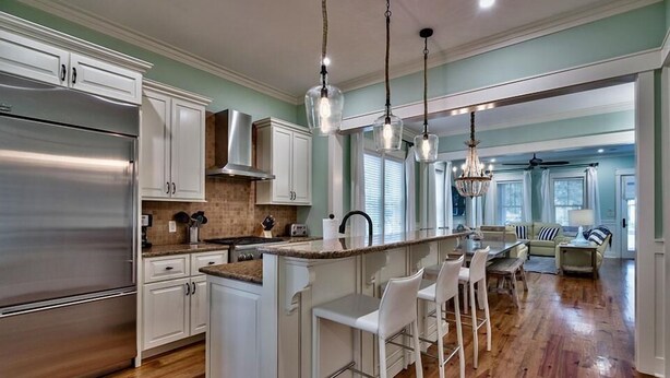 A spacious kitchen with white cabinetry, a stainless steel refrigerator, and a central island with bar stools. - Summer Dreams 4 Bedroom Holiday Home by Five Star Properties (Santa Rosa Beach)