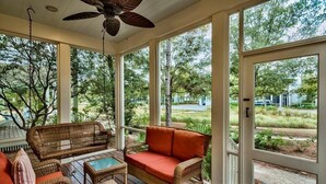 A covered porch with wicker furniture, a ceiling fan, and large windows overlooking a garden. - Summer Dreams 4 Bedroom Holiday Home by Five Star Properties (Santa Rosa Beach)